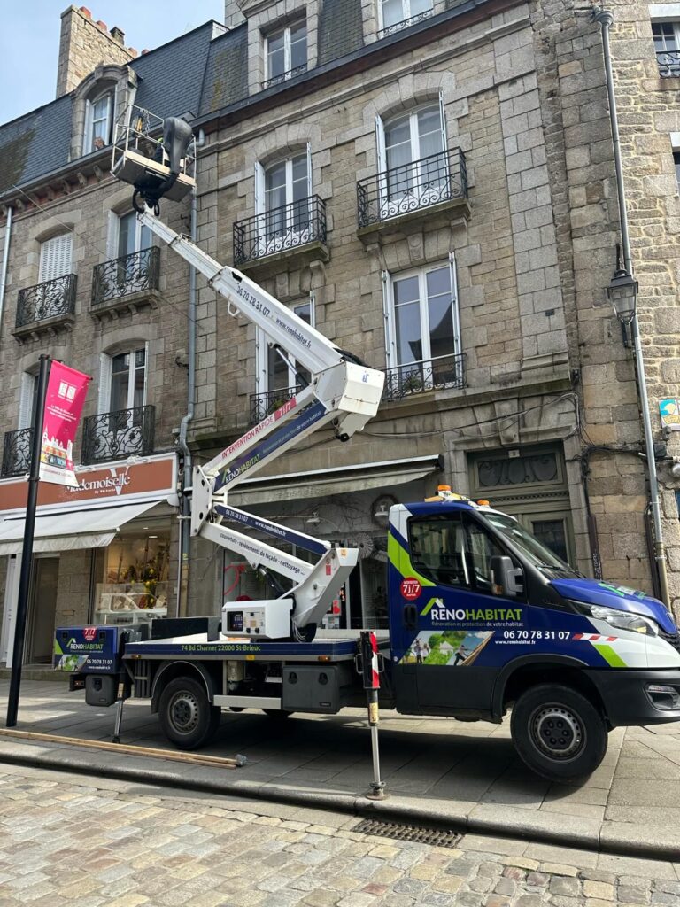 Camion nacelle Réno Habitat déployé devant un immeuble en pierre du centre-ville de Saint-Brieuc pour une intervention de couverture en hauteur.