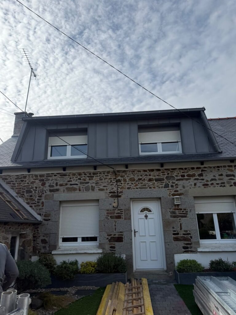 Façade en pierre d'une maison bretonne après rénovation de la lucarne et habillage en zinc anthracite par Réno Habitat.