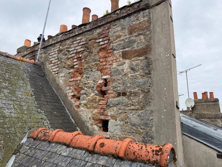 Souche de cheminée en pierre et brique fortement dégradée, joints creusés et briques déchaussées, avant réfection par Réno Habitat à Saint-Brieuc.