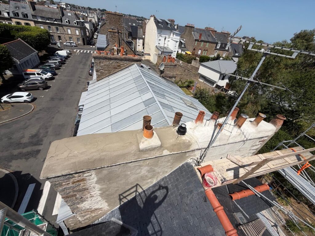 Souche de cheminée entièrement reprise au mortier avec mitrons en terre cuite conservés, vue plongeante sur les toits de Saint-Brieuc.